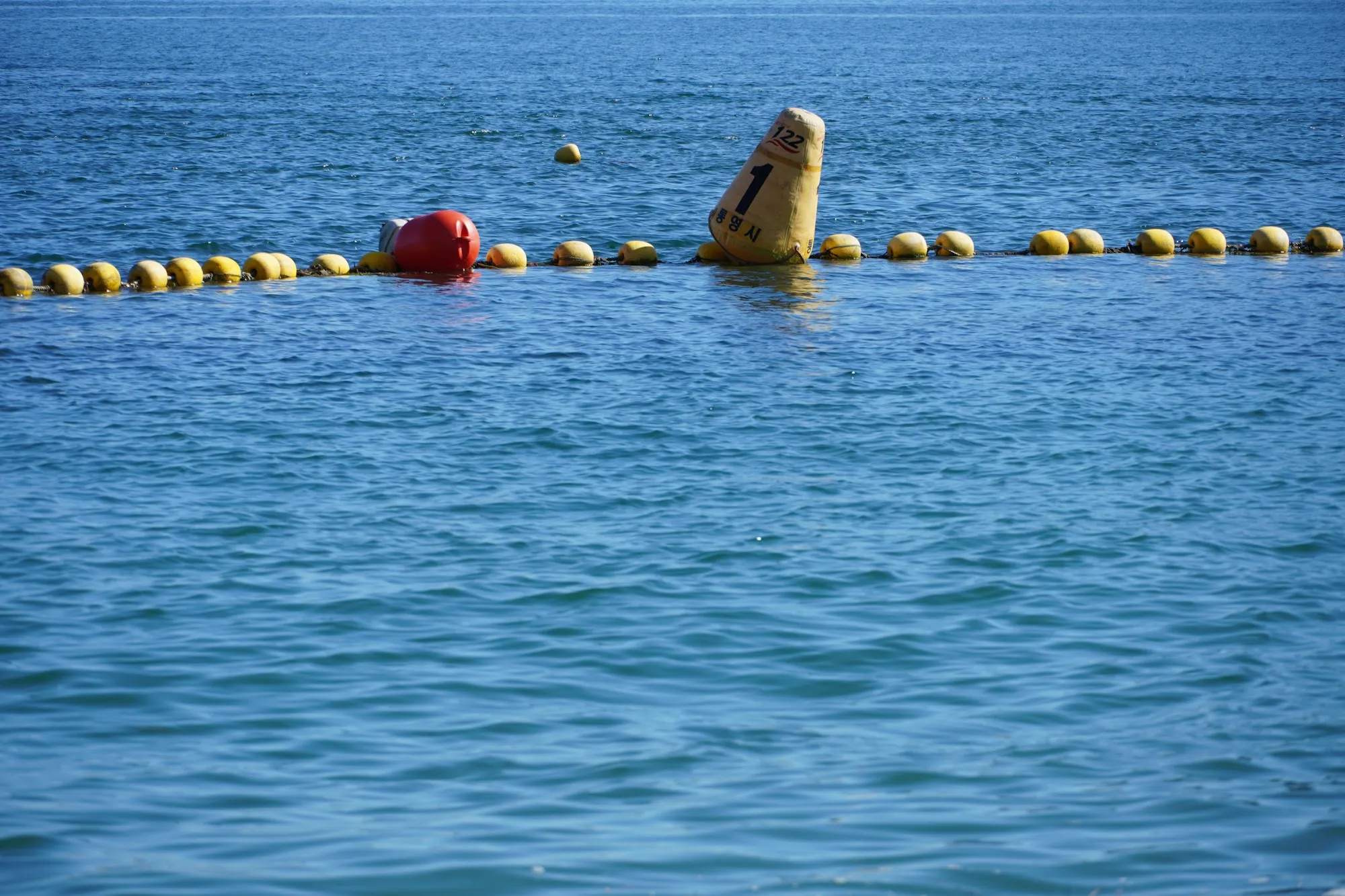 Yellow and red fishing buoys piled together, one marked with the name of Tongyeong city