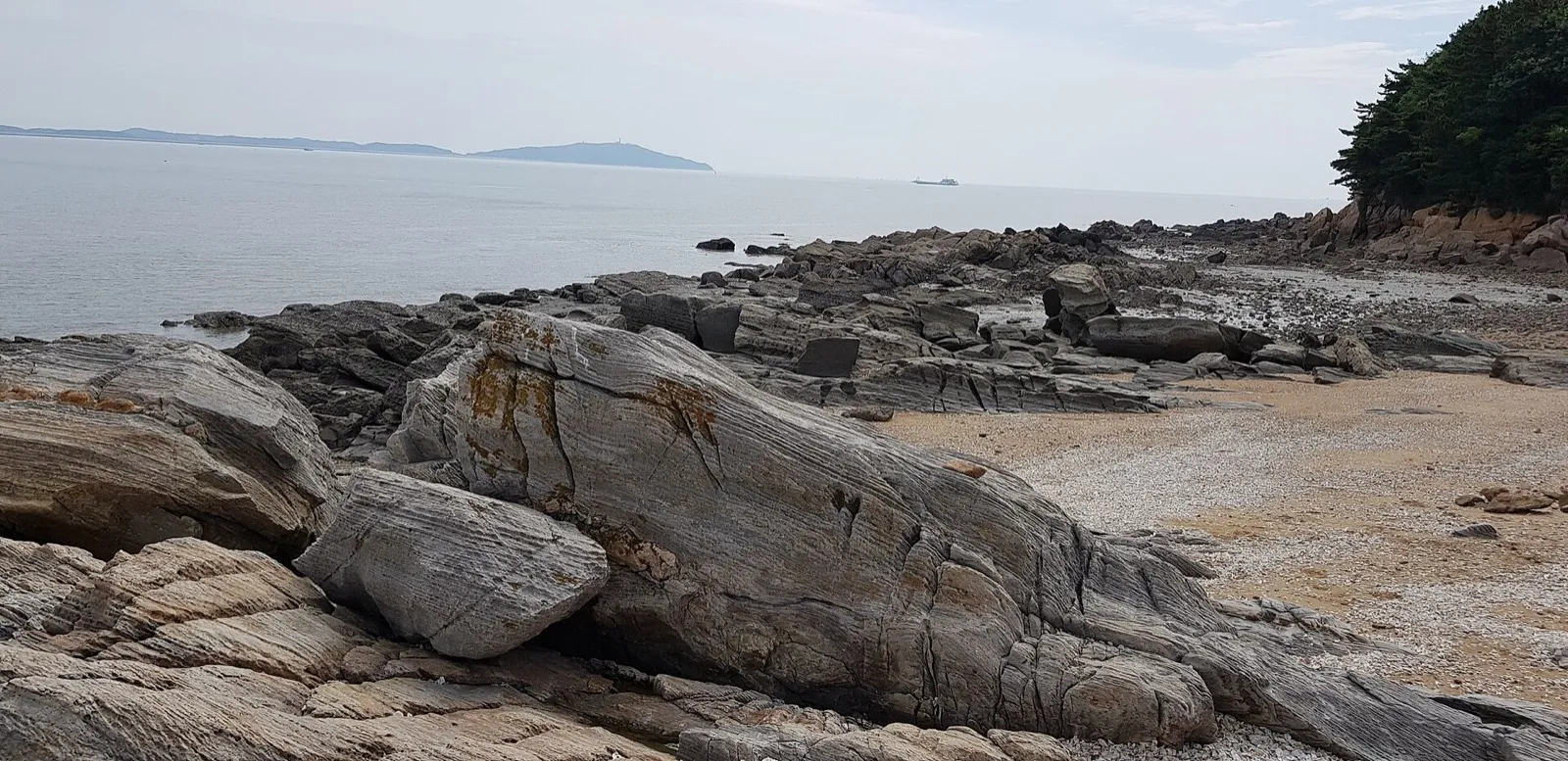 Layered, striped rocks along a beach on Modo, with the tide out
